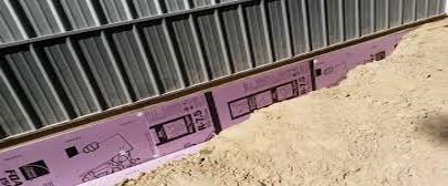 Rigid foam insulation installed around a pole barn foundation.