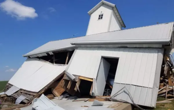 Wind-damaged pole barn with failed wall and roof sections after severe wind loads.