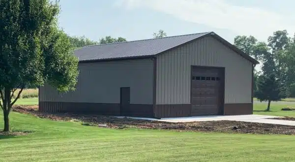 Post-frame building with steel siding, large overhead door, and open-span garage space.