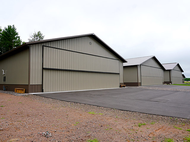 Post-frame airplane hangar buildings with large sliding doors, steel siding, and multi-unit aviation storage layout