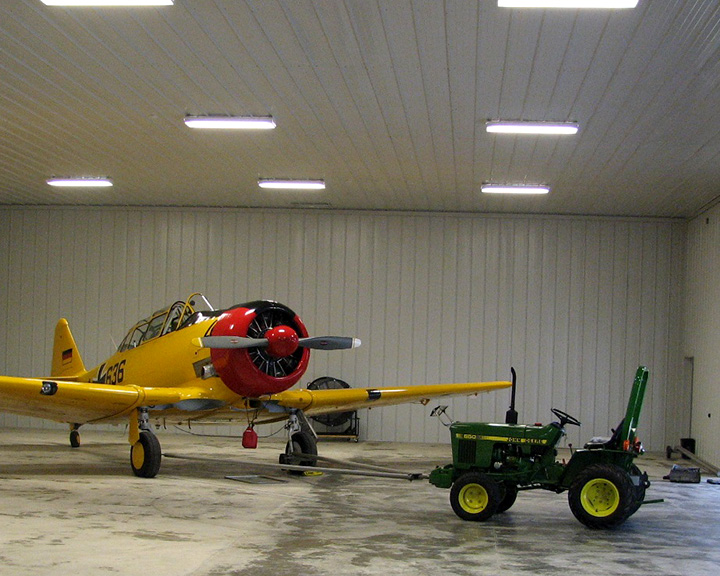 Post-frame airplane hangar interior with steel liner panels, aircraft storage, and equipment space