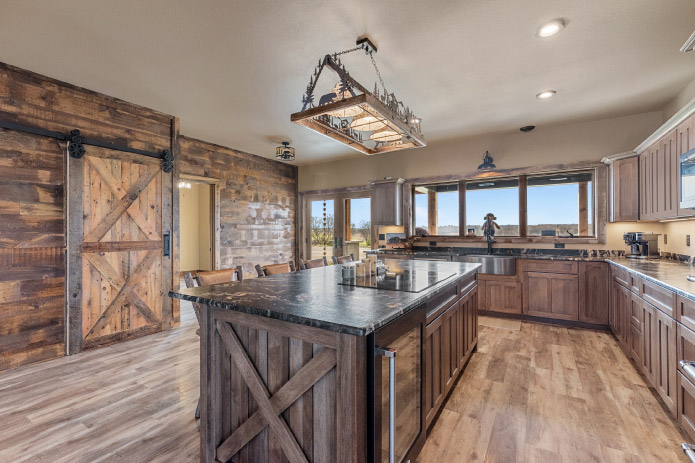 Barndominium Kitchen with Rustic Wood Finishes Rustic barndominium kitchen with large island, wood cabinetry, and sliding barn door