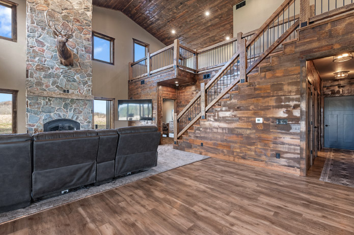 Barndominium Living Room with Stone Fireplace and Loft Barndominium living room with stone fireplace, wood staircase, and open loft