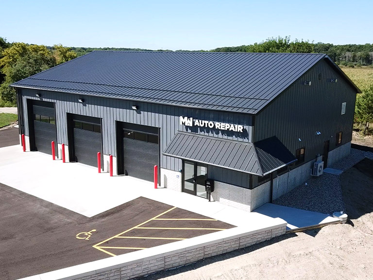 Auto Repair Shop with Covered Customer Entry and Multiple Bays | Walters Buildings Auto repair building with steel siding, multiple overhead doors, and covered customer entrance