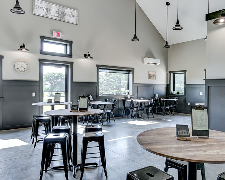 Distillery tasting room interior with seating, large windows, and customer-focused layout