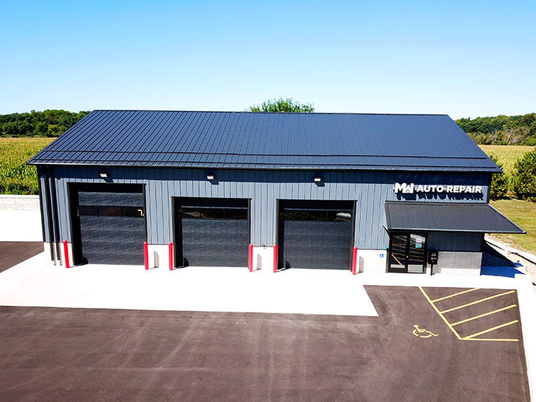 Auto repair shop building with steel siding, overhead garage doors, and customer entrance