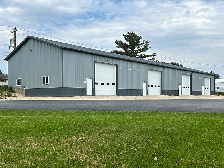 Commercial warehouse building with steel siding, multiple overhead doors, and walk doors for access