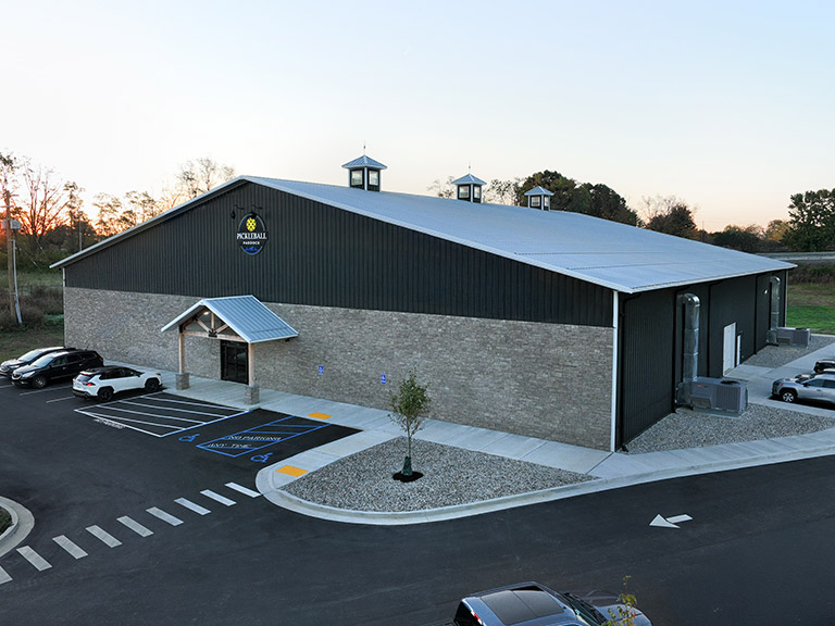 Commercial recreation building with steel siding, cupolas, and covered entry for customer access