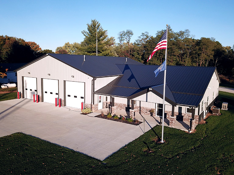 Municipal post frame building with overhead garage doors, steel siding, and office space for fire station or public works facility