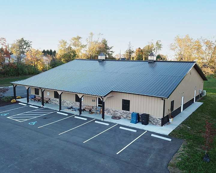 Post frame community building with covered porch, steel roof, and parking lot for municipal and recreation use