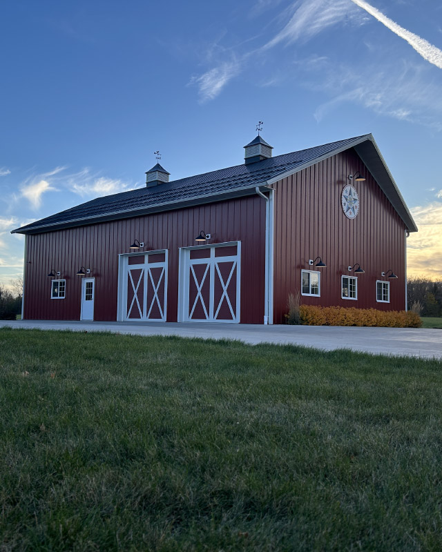 Red Equipment Storage Building with Overhead Doors and Cupolas | Walters Buildings Red equipment storage building with white overhead doors, cupolas, and exterior lighting