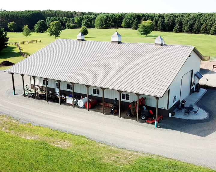 Equipment storage building with extended covered lean-to for machinery protection and easy access