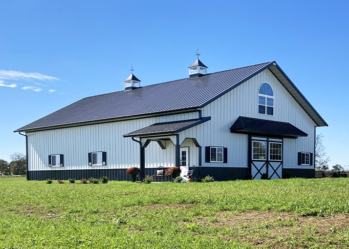Post-frame detached garage with steel siding, overhead doors, cupolas, and covered entry