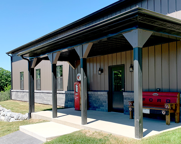 Post-frame garage building with steel siding, covered porch, and residential-style entry