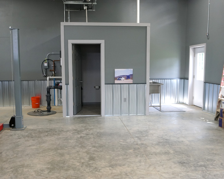 Post-frame garage interior with steel liner panels, utility room, and open floor space