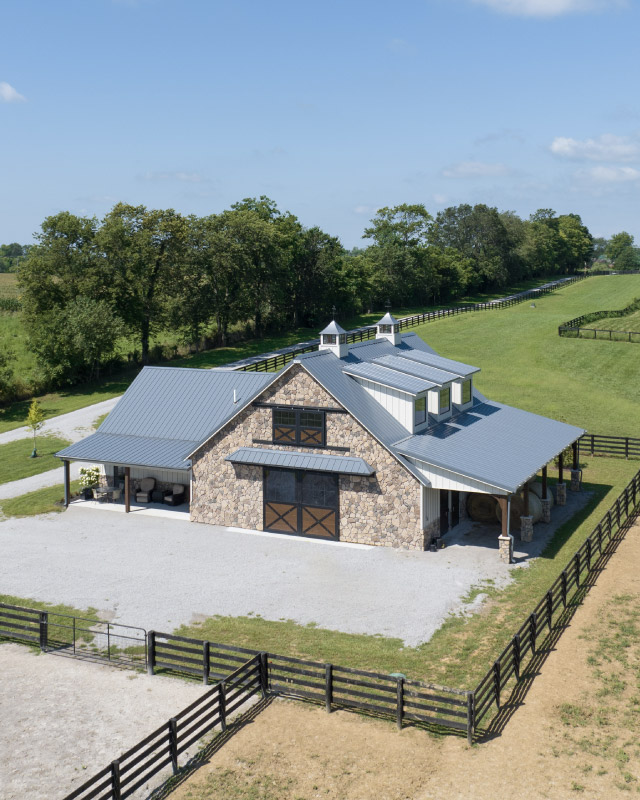 Custom Horse Barn with Stone Exterior and Cupolas | Walters Buildings Custom horse barn with stone exterior, cupolas, and fenced pasture