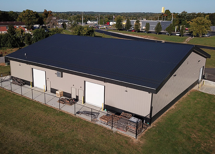 Industrial warehouse with steel siding, overhead doors, and fenced outdoor storage area