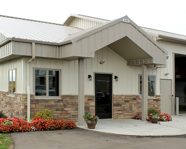 Industrial building office entrance with steel siding, covered entry, and stone wainscot