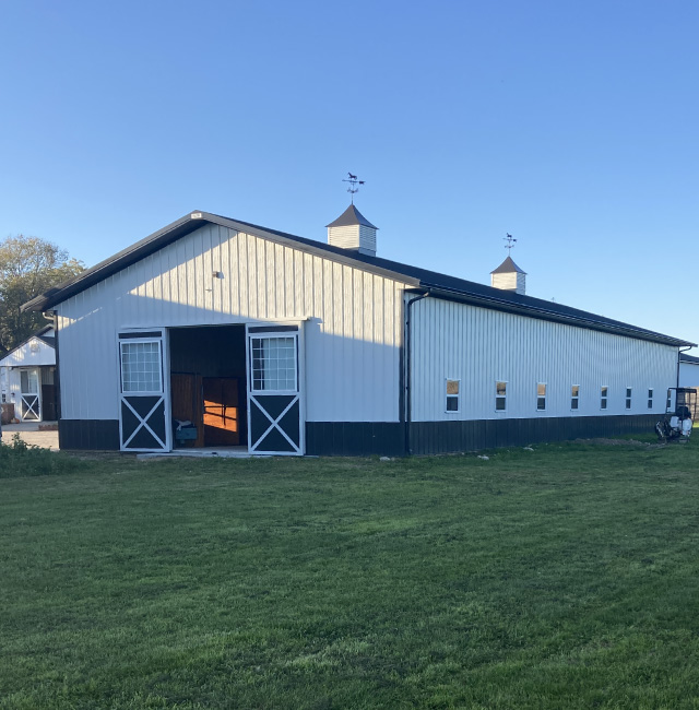 Stall barn with sliding doors and roof cupolas at Integrity Farms horse facility