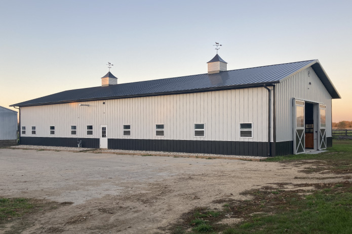 Stall barn exterior with cupolas and sliding doors at Integrity Farms horse facility
