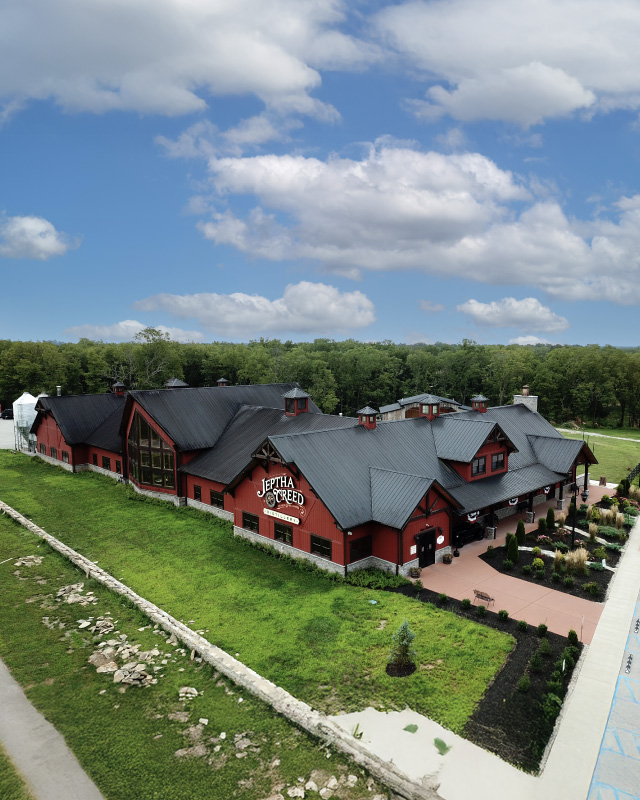 post frame distillery building with black metal roof cupolas tasting room and production facility