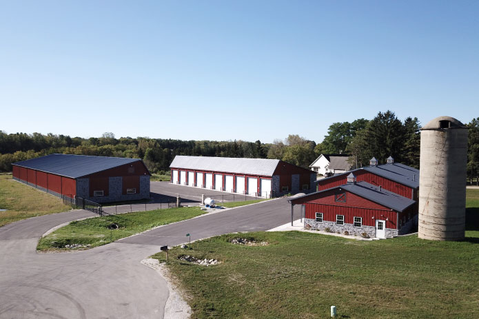 Modern Storage Facilities in Waukesha Wisconsin | Lone Silo Storage Lone Silo Storage facilities in Waukesha Wisconsin featuring multiple red post frame storage buildings with gray metal roofs and outdoor storage units.