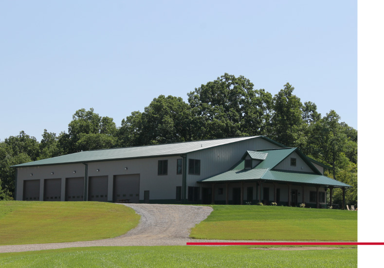 Large hunting cabin lodge with green metal roof and attached garage bays