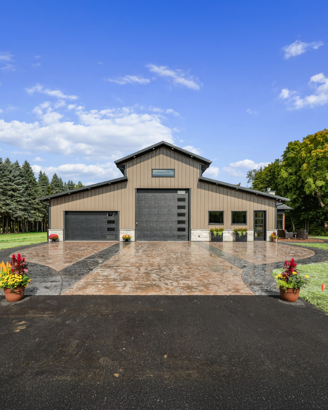 Custom Monitor Barndominium Exterior Monitor Barndominium in Kenosha, Wisconsin Monitor barndominium with raised center roof section, tan steel siding, and black garage doors in Kenosha, Wisconsin