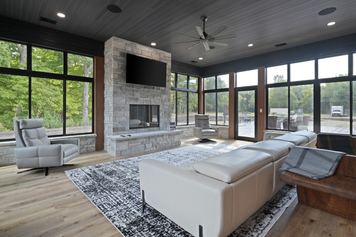 Monitor Barndominium Four-Season Living Room Four-season living room inside a custom monitor barndominium with stone fireplace and large windows