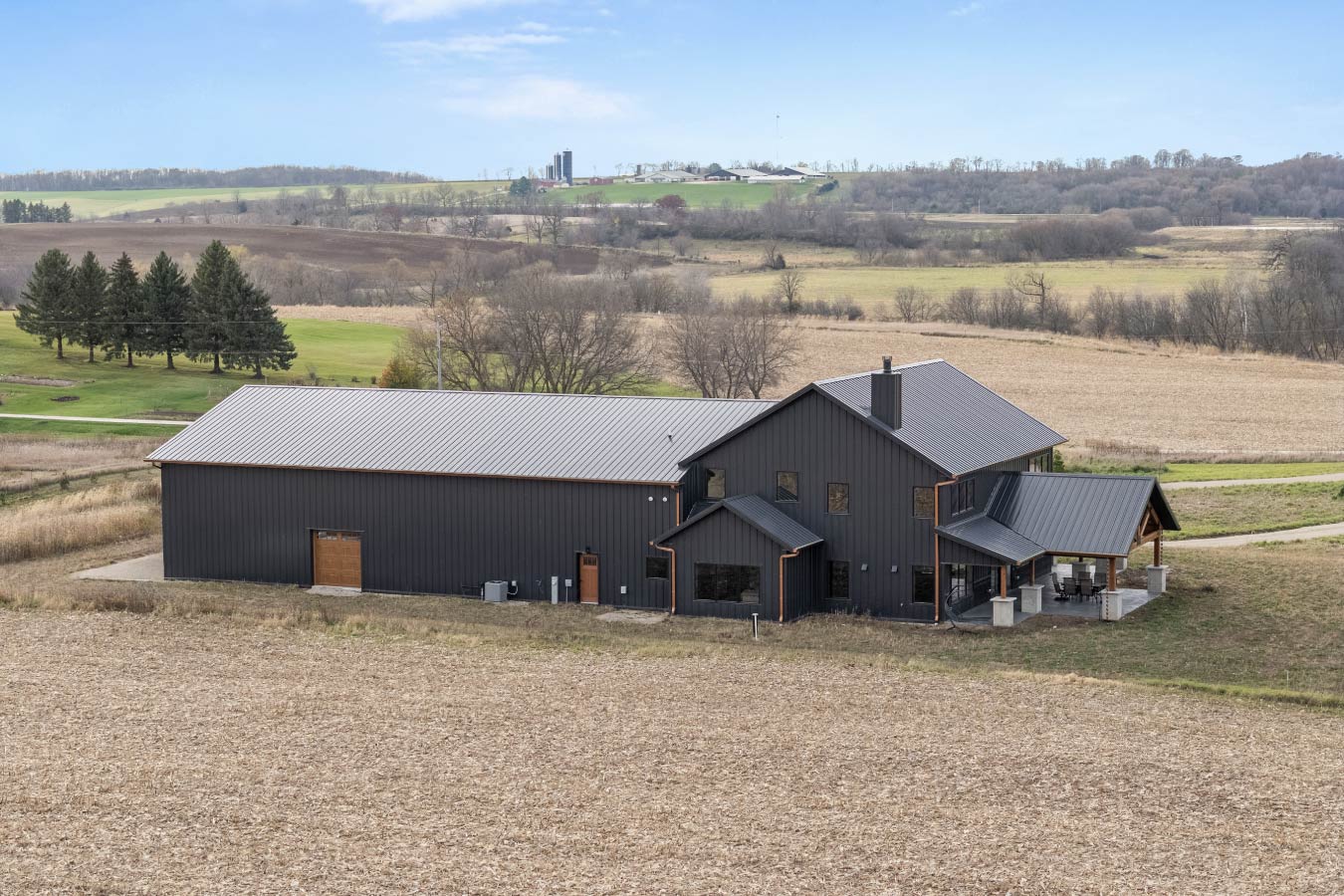 Rural barndominium with black steel siding and attached shop building