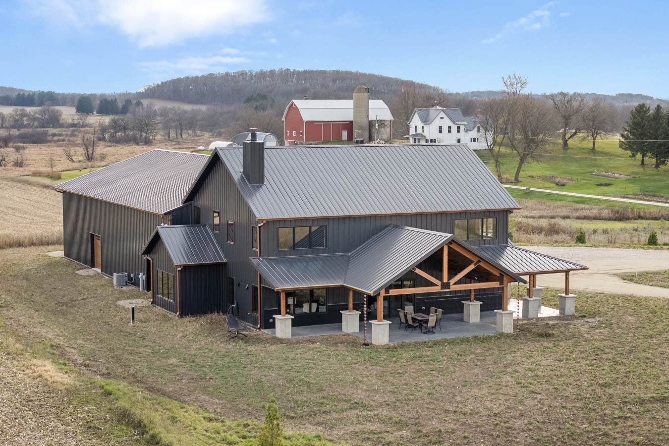 Black steel barndominium with metal roof and timber framed covered porch