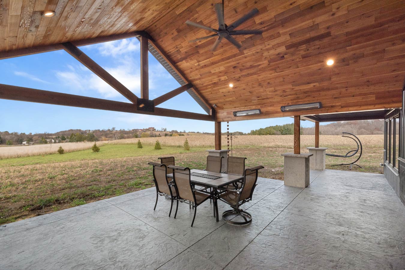 Covered barndominium patio with timber trusses and wood ceiling