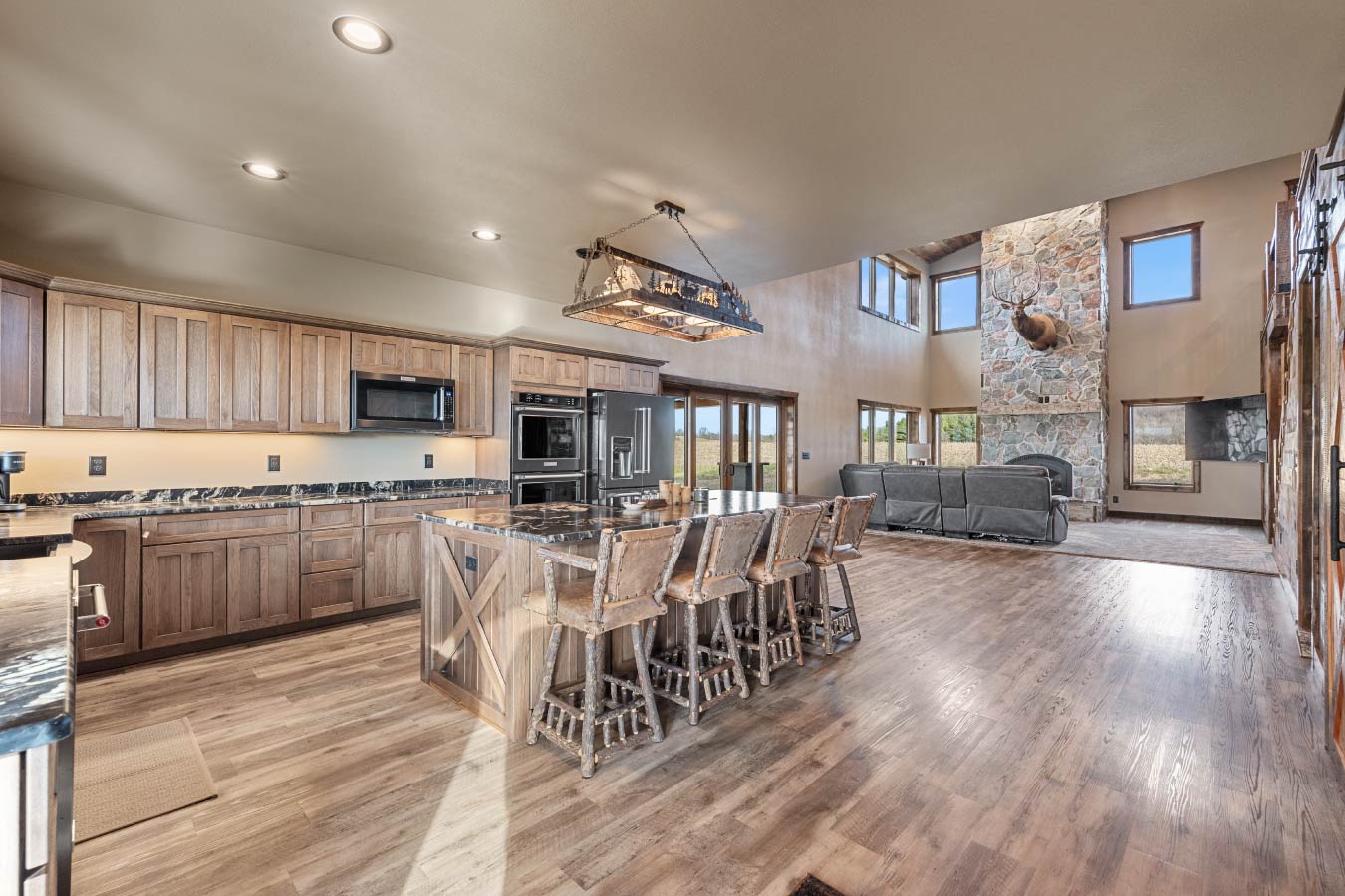 Open concept barndominium kitchen and living room with stone fireplace