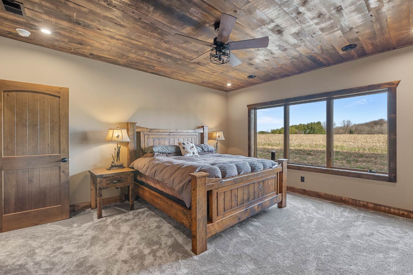 Barndominium bedroom with rustic wood ceiling and large picture window