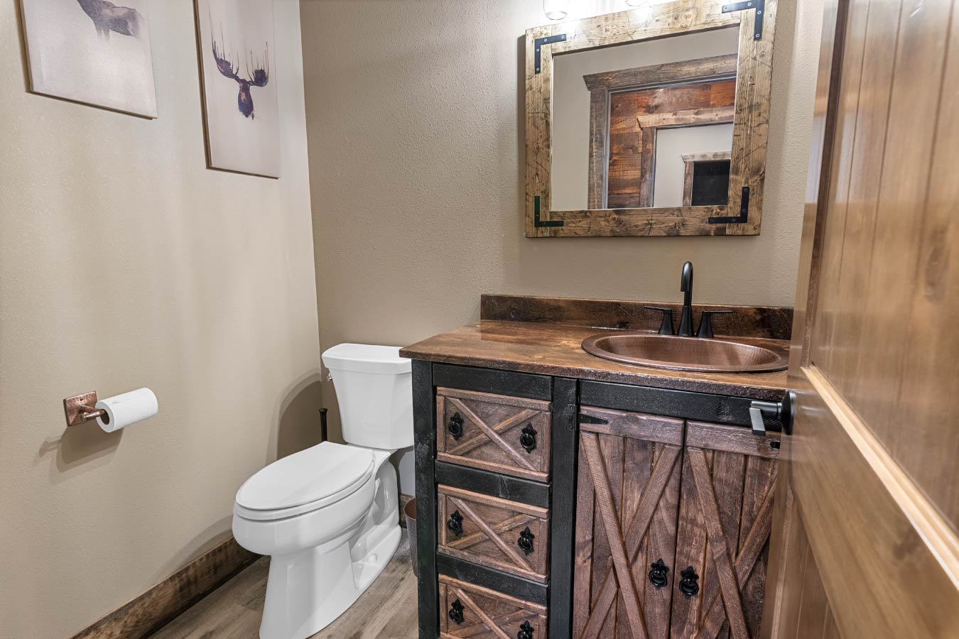 Barndominium bathroom with rustic wood vanity, copper sink, and barn-style cabinet doors