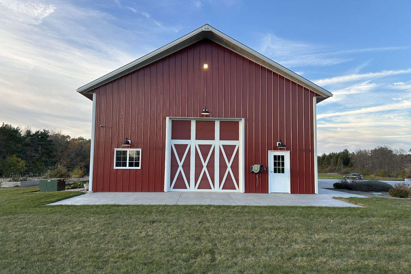 Equipment storage building with large overhead door, entry door, and exterior lighting