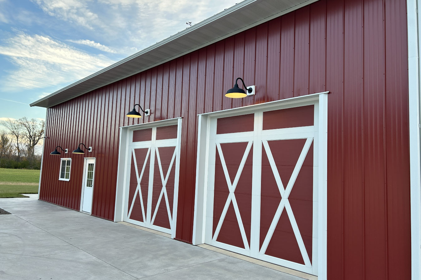 Equipment storage building with large overhead doors, white trim, and exterior gooseneck lighting