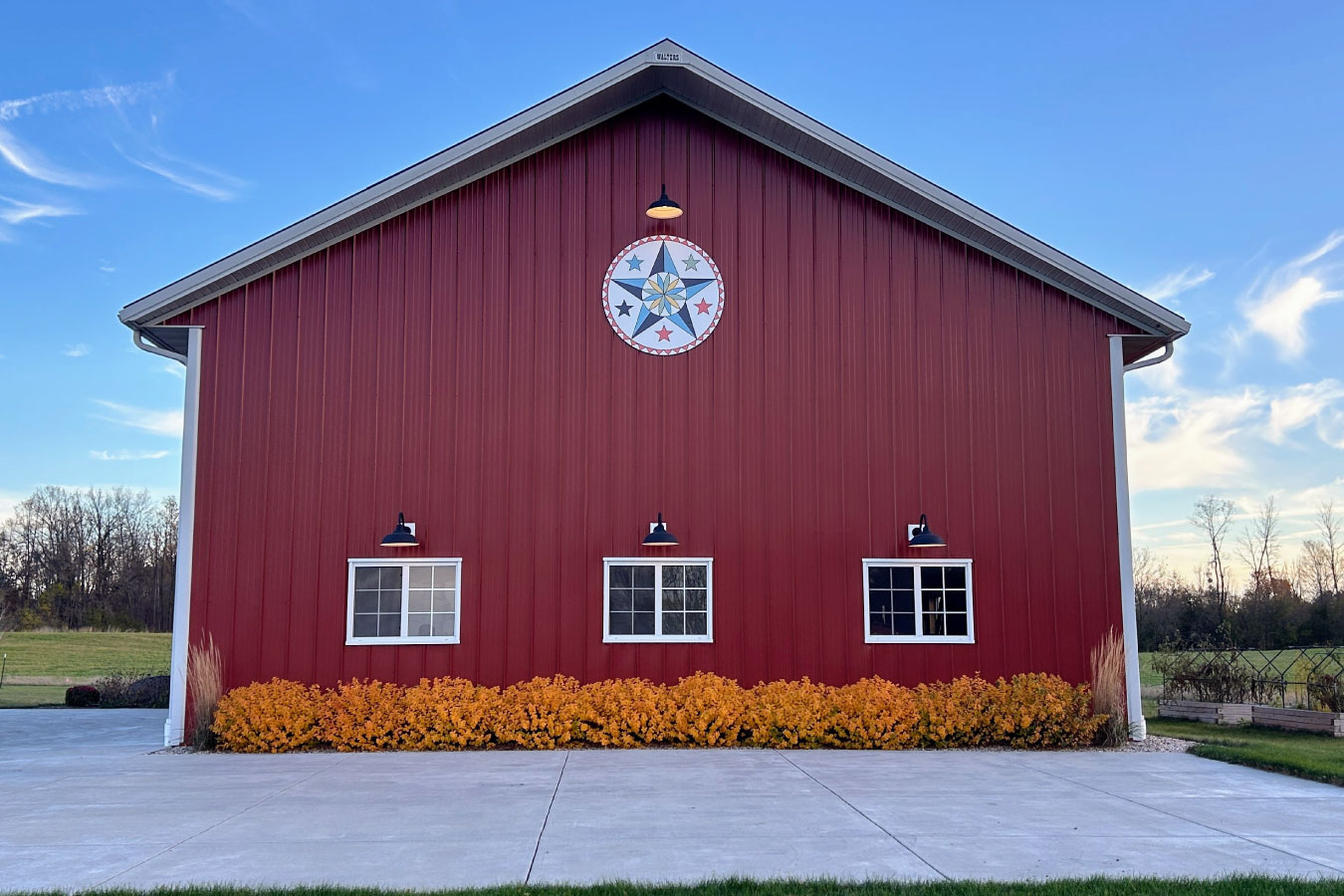 This equipment storage building features a decorative barn star accent that adds a classic agricultural touch to the structure. Paired with durable steel siding and exterior lighting, the design blends traditional barn style with modern functionality for equipment storage.