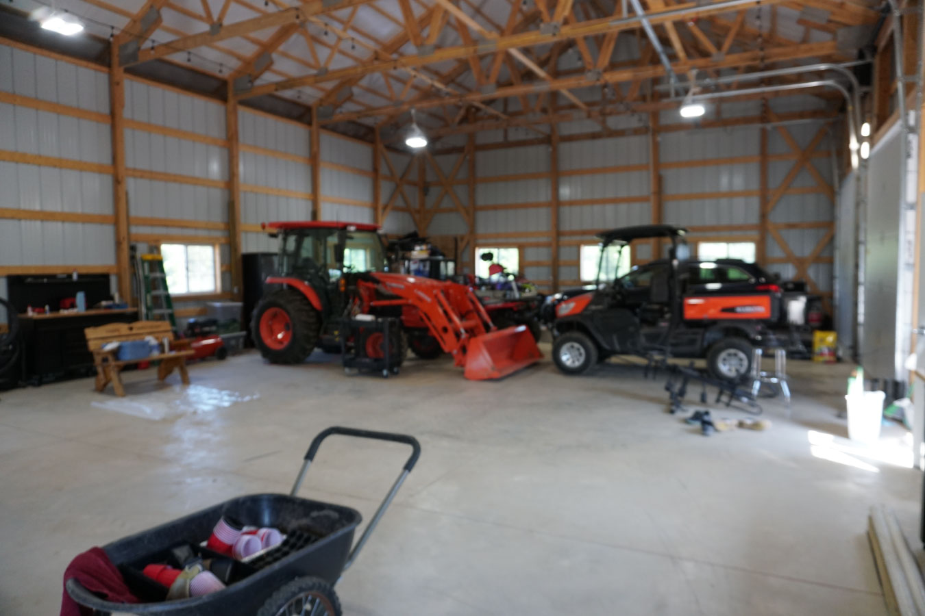 Equipment storage building interior with tractor, utility vehicle, and open floor space