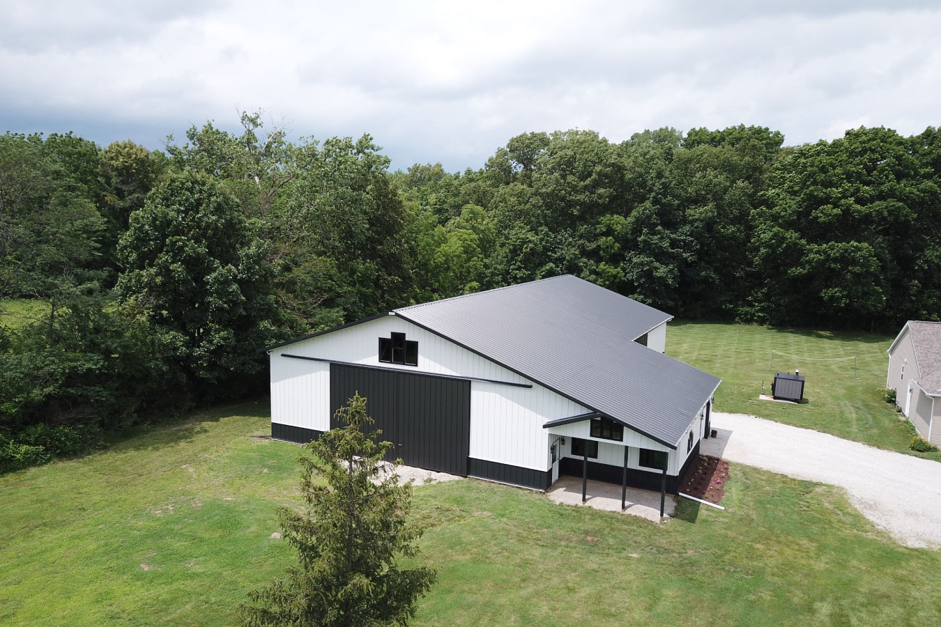 Equipment storage building with large sliding door, porch, and surrounding open land