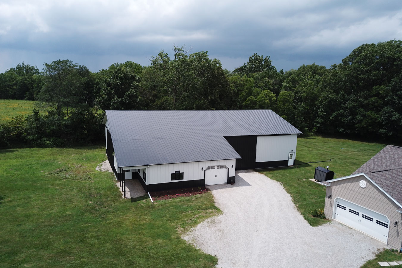 Equipment storage building with gravel driveway, large access door, and open yard