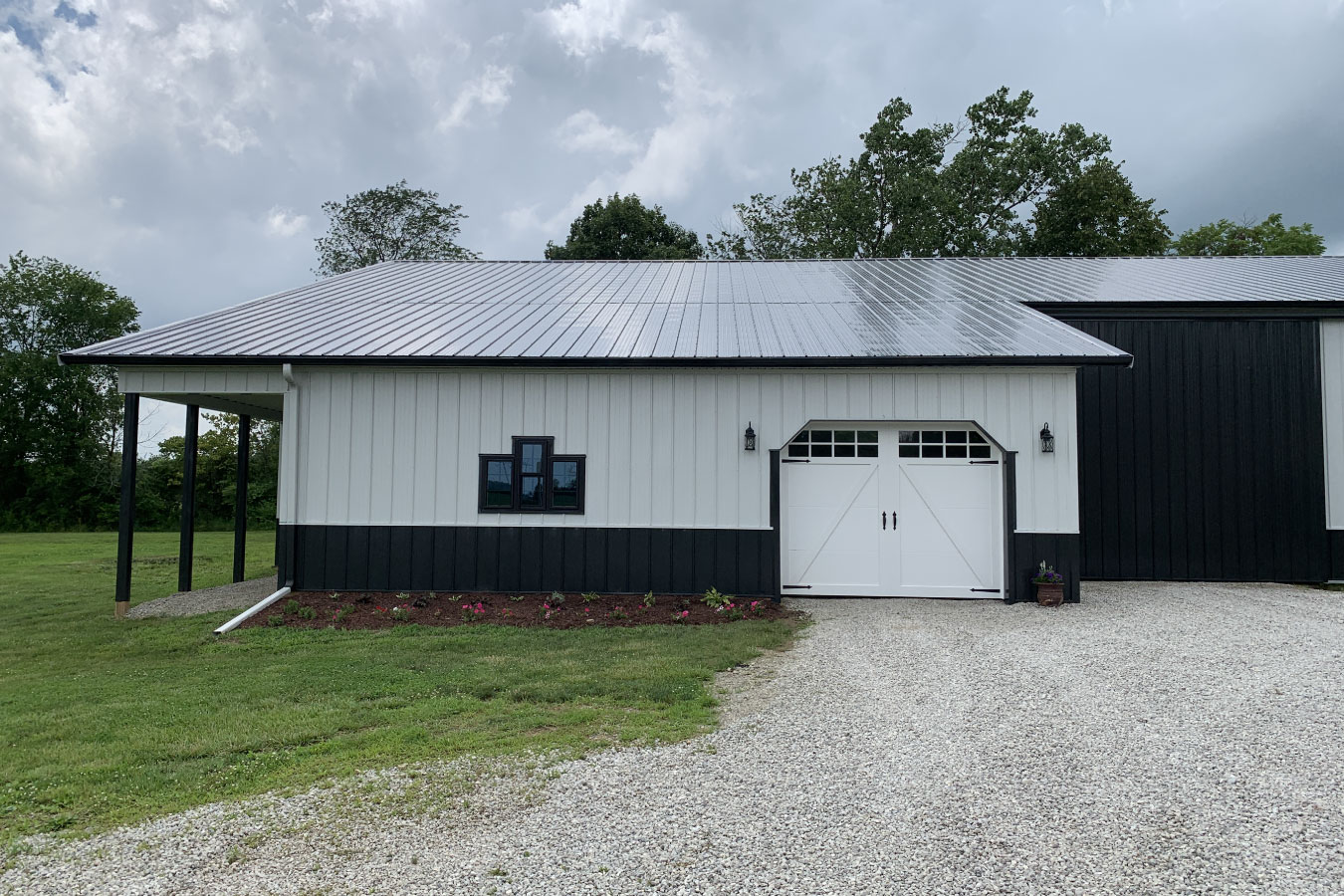 Equipment storage building with overhead garage door, porch, and gravel approach
