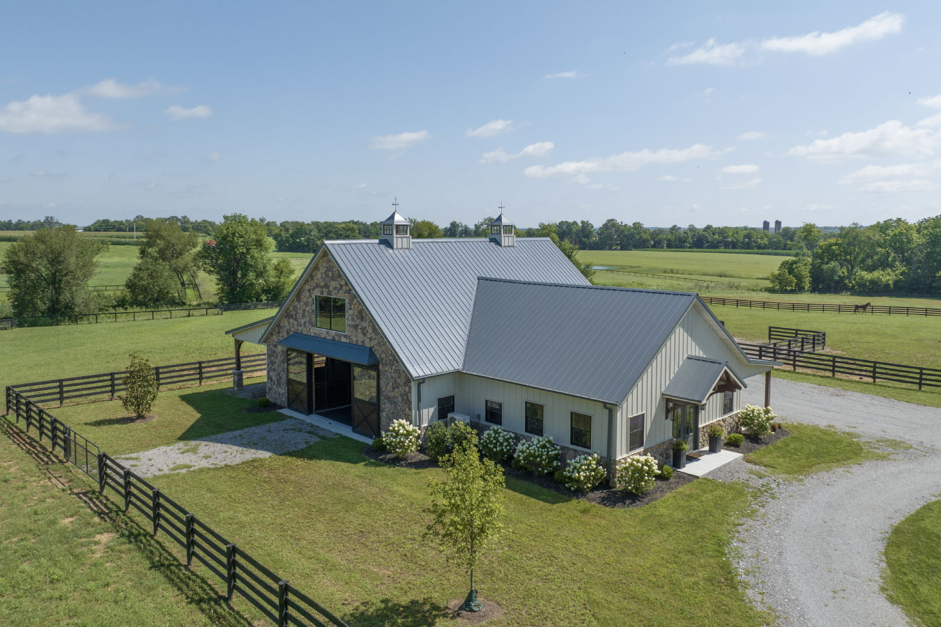 Horse barn with living quarters surrounded by fenced pasture and countryside