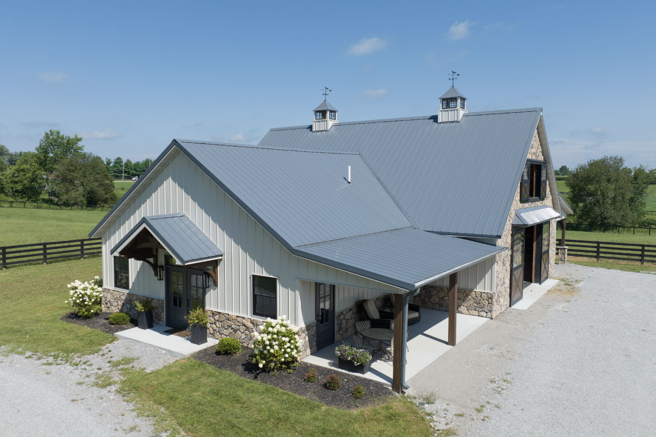 41-3857 Horse barn with living quarters featuring white steel siding, stone accents, and cupolas