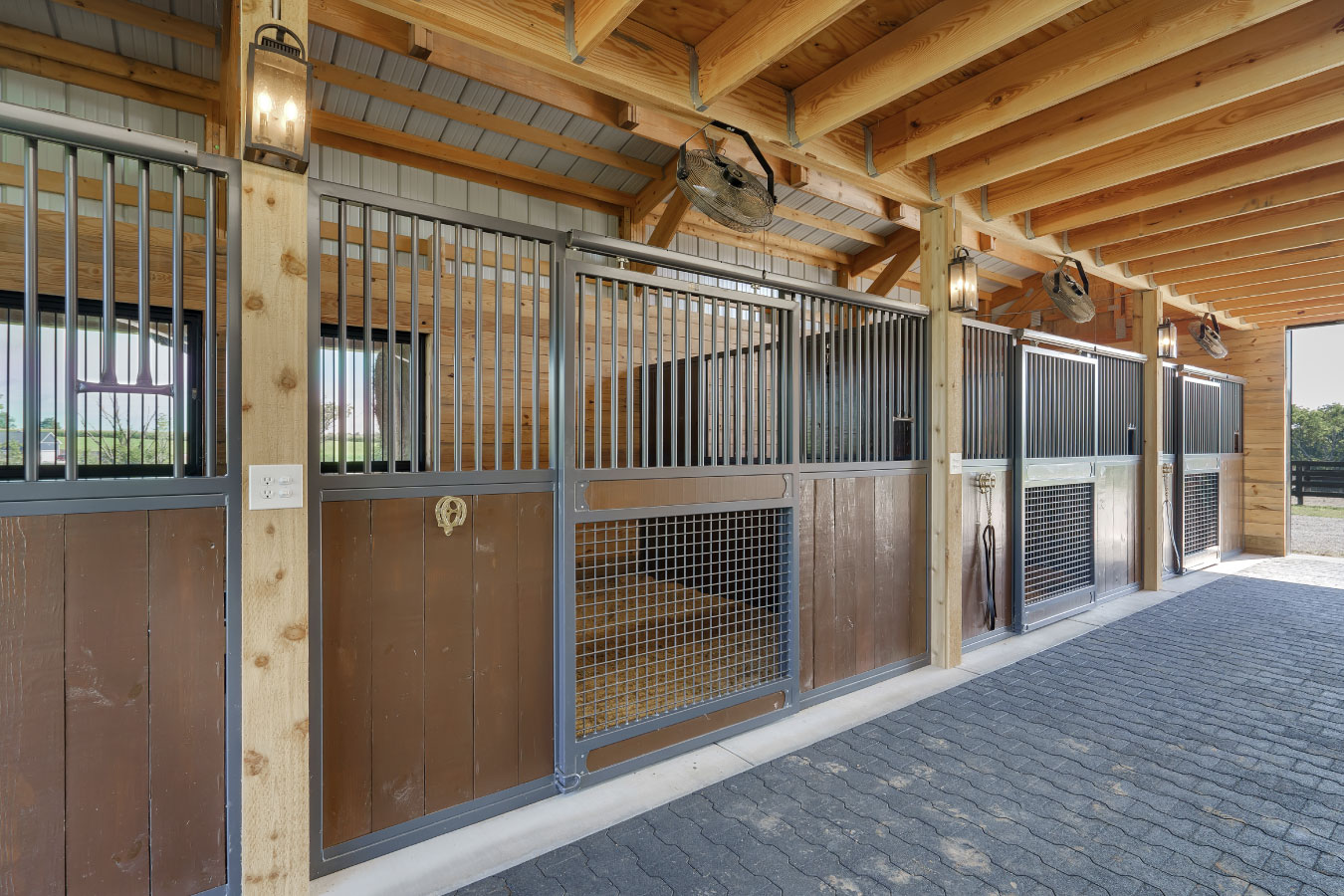 Horse barn interior with custom horse stalls and rubber paver aisle