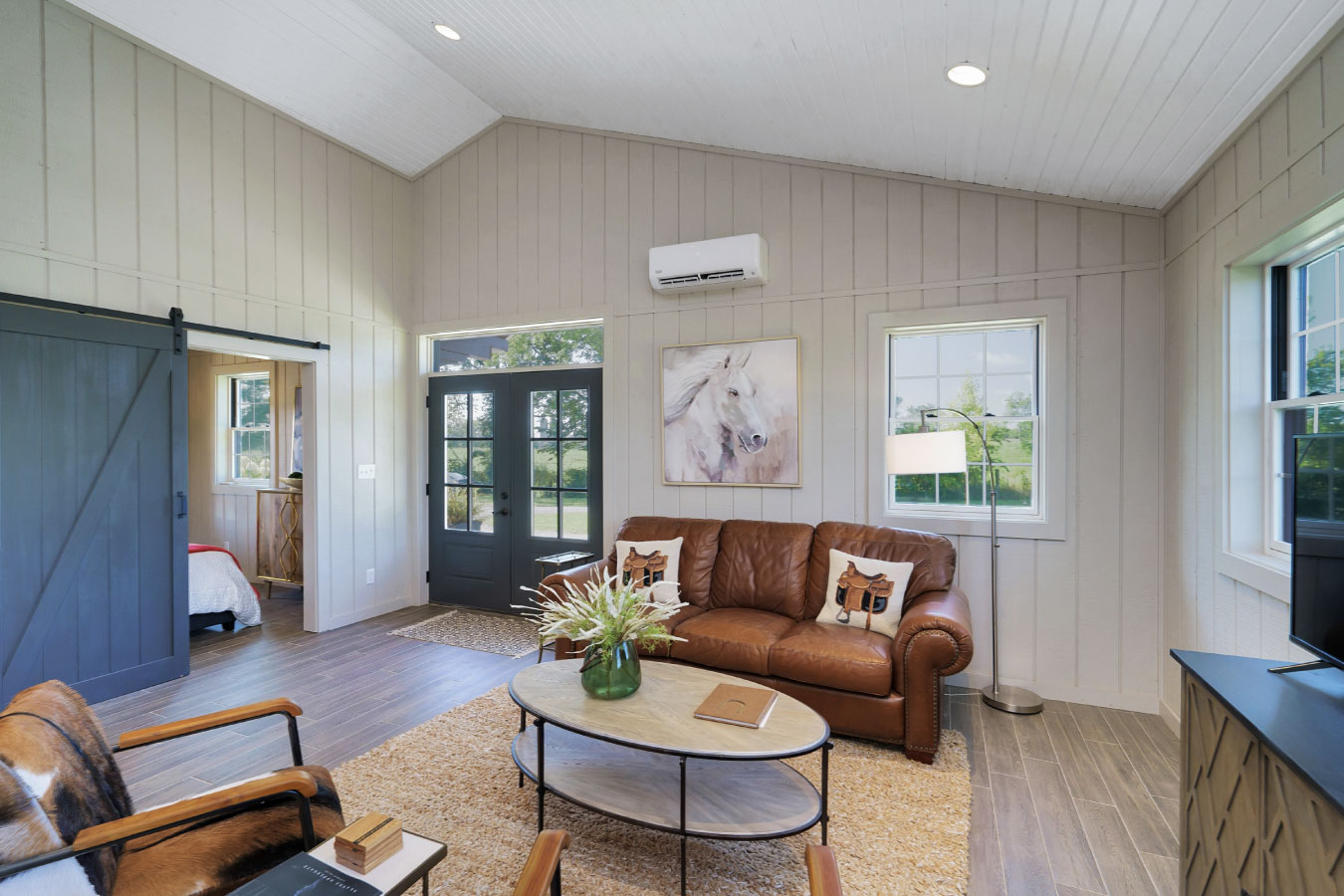Horse barn living quarters lounge with leather sofa and sliding barn door