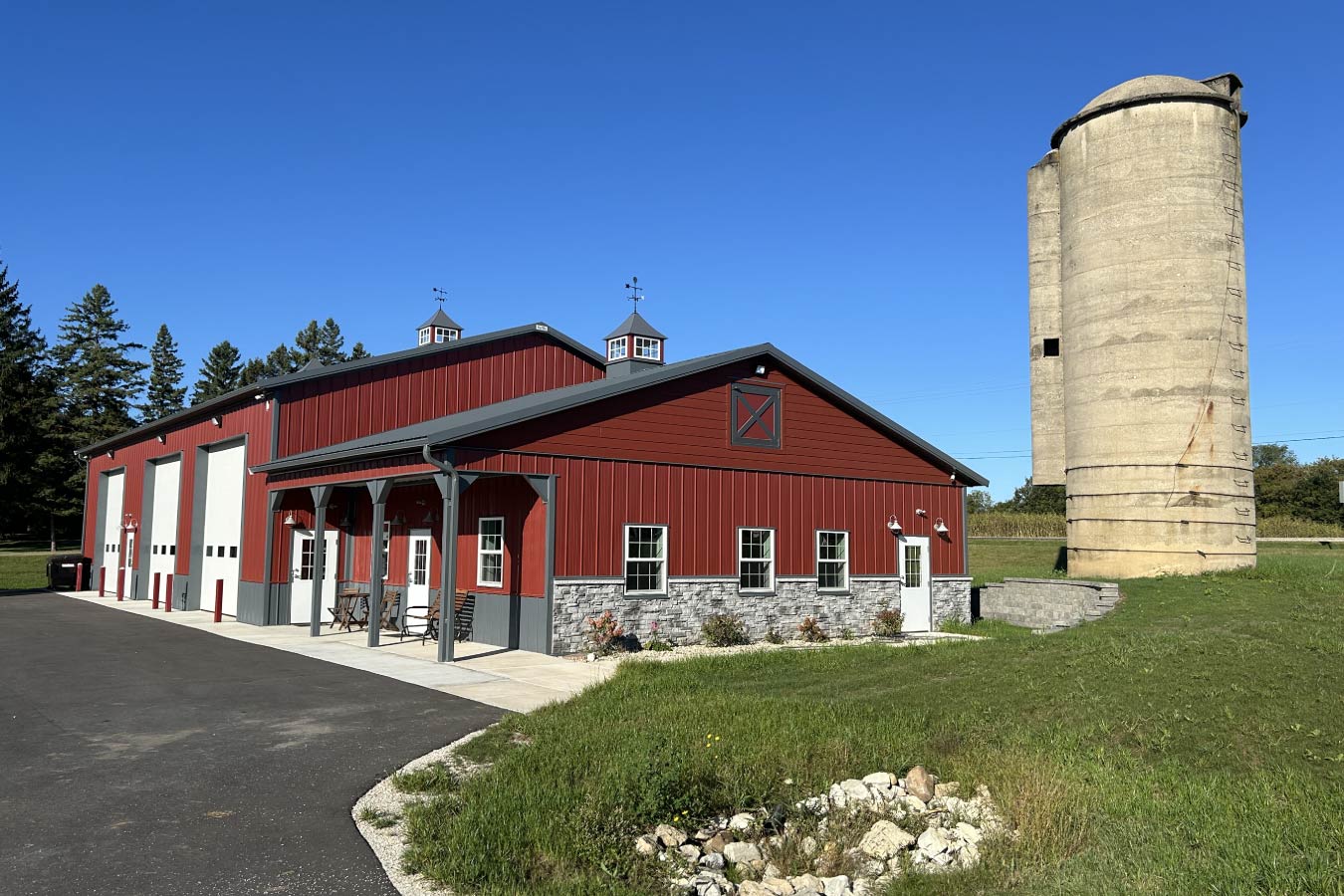 95-1960 Lone Silo Storage facility in Waukesha Wisconsin with red post frame storage building, gray metal roof, stone wainscot, and historic concrete silo.