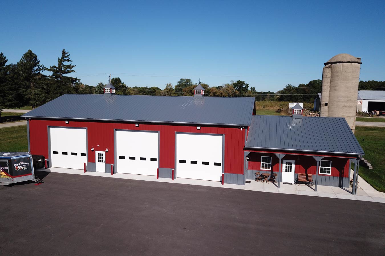 Lone Silo Storage facility in Waukesha Wisconsin with red post frame storage building, gray metal roof, and multiple large storage unit doors. Three Overhead Doors