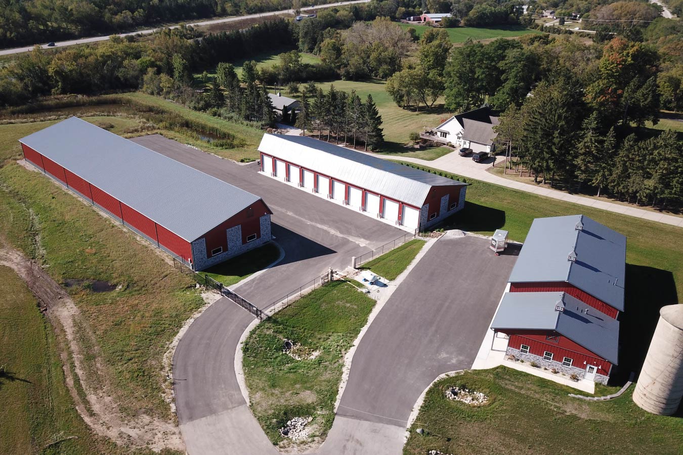 Aerial view of Lone Silo Storage facilities in Waukesha Wisconsin with multiple red post frame storage buildings and gray metal roofs. Aerial View of Storage Buildings and Office Space