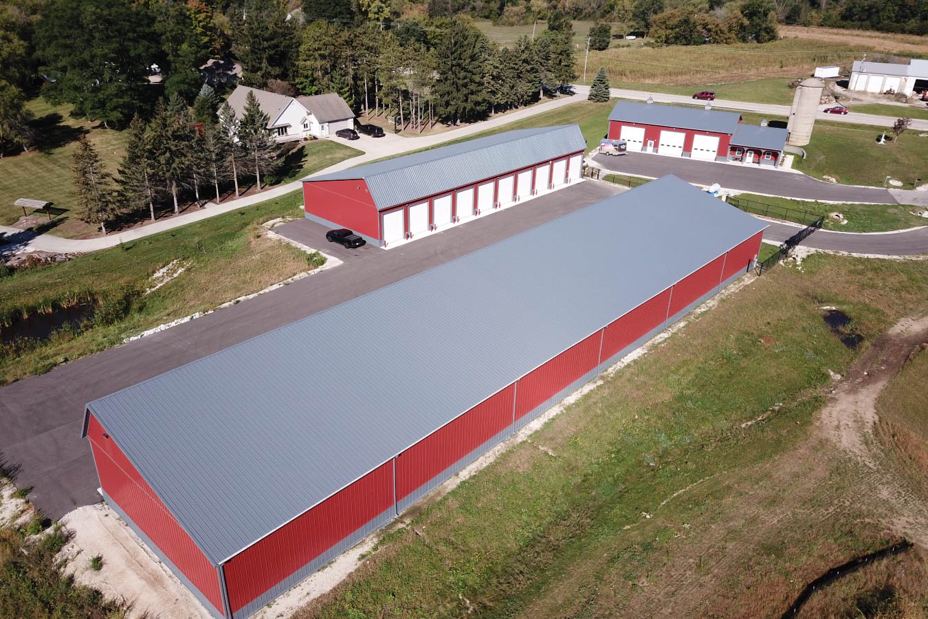 Aerial view of Lone Silo Storage facilities in Waukesha Wisconsin with multiple red post frame storage buildings and gray metal roofs. Aerial View of Storage Buildings